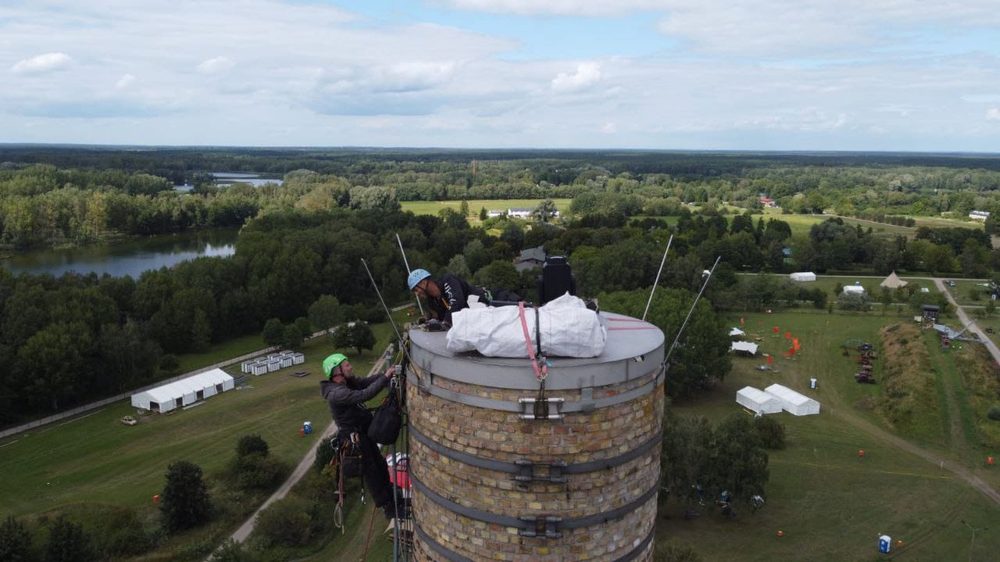 Two technicians working atop a brick chimney tower