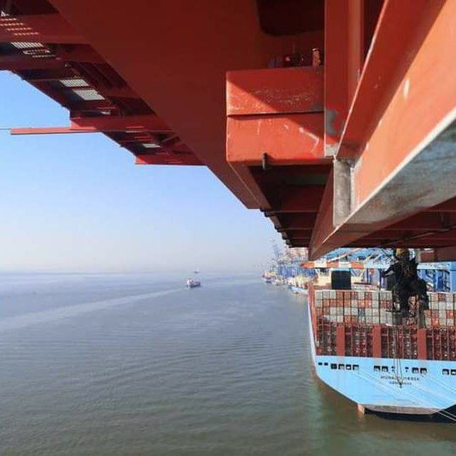View from beneath a crane boom over a container ship