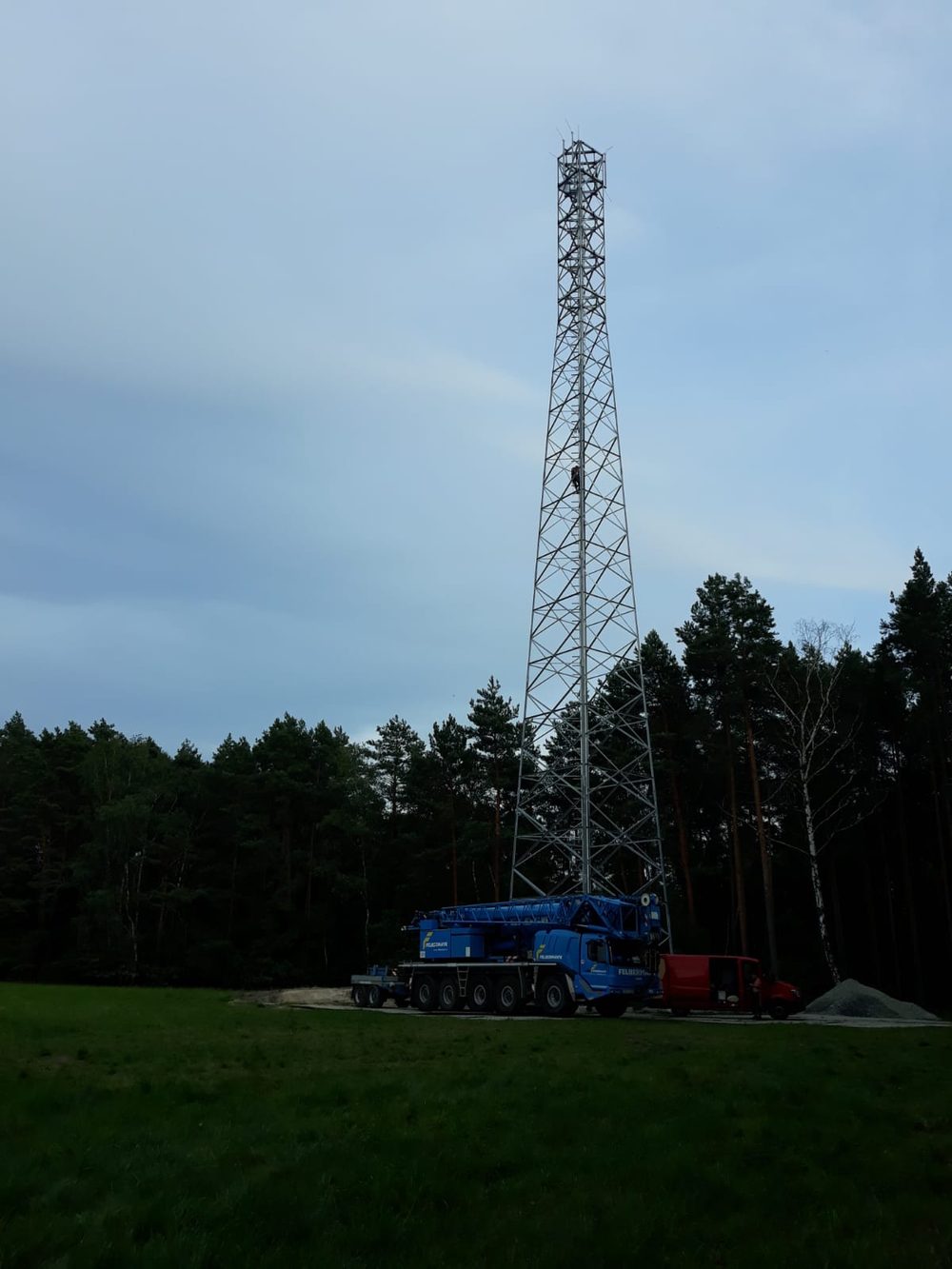 Climbing a lattice transmission tower beside a crane